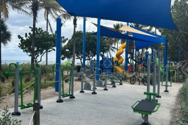 ExoFit outdoor fitness stations with shade sails on a waterfront park trail in spring.