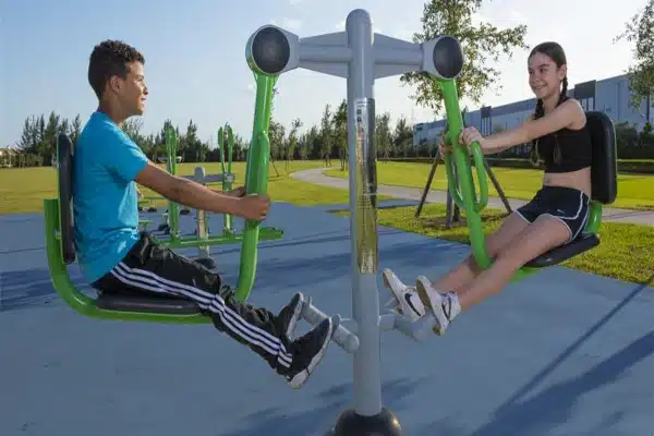 Two children using the ExoFit 2-person leg press in an outdoor area.